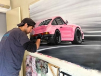 Artista pintando un Porsche clásico en un lienzo