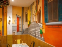 Mural panorámico con fachadas italianas y mobiliario del restaurante
