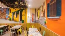 Mural panorámico con fachadas italianas y mobiliario del restaurante