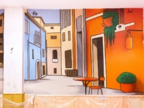 Detalle del mural con fachadas amarillas y calle en perspectiva