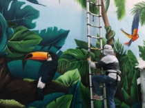 Graffitero-pintando-mural-de-selva-en-patio